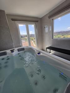 a large bath tub in a bathroom with two windows at Caia House in Ourondo +46 photos