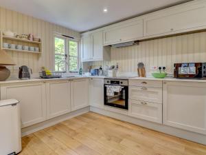 a kitchen with white cabinets and an oven at Meadow Barn in Pulborough