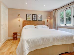 a bedroom with a large bed with white sheets at Meadow Barn in Pulborough