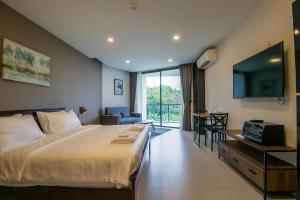 a hotel room with a large bed and a tv at Escape Condominiums Beachfront Suites - Mae Phim in Rayong +131 photos