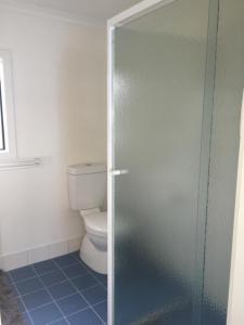 a bathroom with a toilet and a glass shower door at Rumah Pantai in Emu Bay