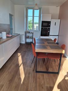 a kitchen with a wooden table and red chairs at Chambres d'hôtes Frehel in Fréhel