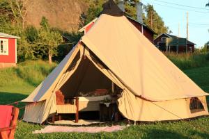 a tent with a bed and a chair in a field at Jennys tent in Saltvik