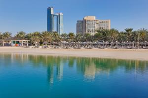 a beach with chairs and umbrellas and a city at InterContinental Abu Dhabi by IHG in Abu Dhabi