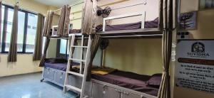 a room with three bunk beds and a sign at Suvidha Dormitory Hotel in Bhuj