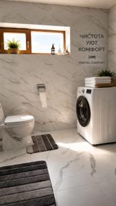 a bathroom with a toilet and a washing machine at Alima in Ottuk
