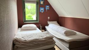 two beds in a small room with a window at Huisje 47 | 8 persons in Gasselte