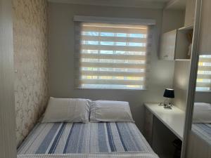 a small bedroom with a bed and a window at Apto completo 2 quarto 2 banheiro universidade Positivo Volvo C garagem in Curitiba