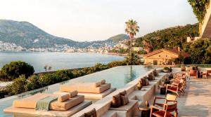 a pool with chairs and a view of the water at Nirema Hotel & Spa Samos - MGallery Collection in Samos