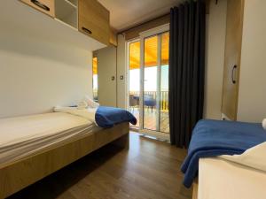 a bedroom with two beds and a balcony at Mobile homes Camp Kozica in Sibinj Krmpotski