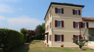 a building with red shuttered windows and a yard at Cà Dei Nonni in Castelfranco Veneto