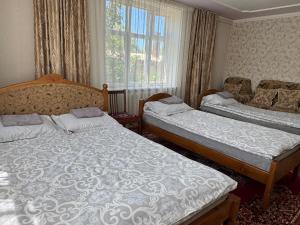 a bedroom with two beds and a window at Meerim Guest House in Bokonbayevo