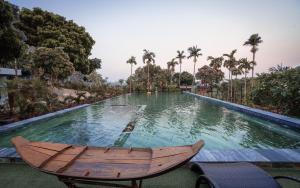 a large swimming pool with a wooden boat in it at De Mémoire Retreat in Tien Xuan