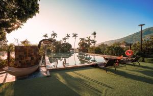 a resort with a pool with palm trees and a mountain at De Mémoire Retreat in Tien Xuan