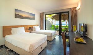 a hotel room with two beds and a desk with a table at Temple Beach Resort in Danang