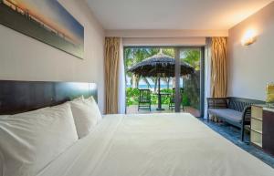 a bedroom with a large white bed and an umbrella at Temple Beach Resort in Danang