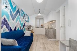 Opera Lane Suites في أوديسا: غرفة معيشة بها أريكة زرقاء ومطبخ