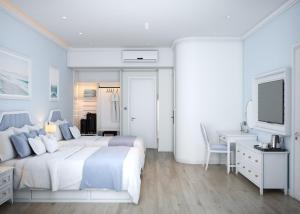 a white bedroom with a large bed and a desk at TTC Lotus Hotel in Phú Quốc
