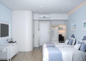 a white bedroom with two beds and a tv at TTC Lotus Hotel in Phú Quốc