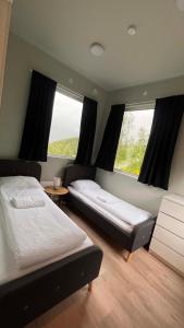 a bedroom with two beds and two windows at Storfossen Hostel in Gratangen
