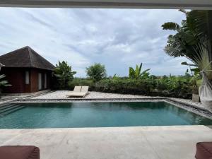a swimming pool with a bench in a yard at Villa Dew Canggu in Kerobokan
