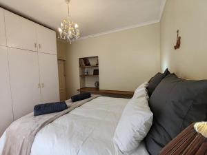 a bedroom with a large white bed with pillows at Caradoc House in Muizenberg