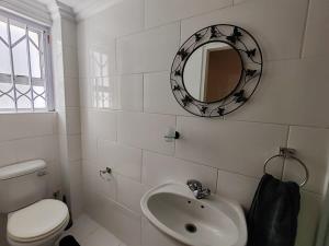 a bathroom with a sink and a toilet and a mirror at Caradoc House in Muizenberg