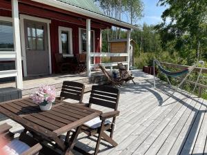 a wooden deck with a hammock and a wooden table and chairs at Revontulet ZH Tulimetsän Kylä in Pieksämäki