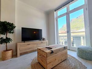 a living room with a tv and a large window at Waveside Stays in Muizenberg