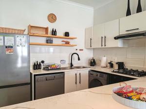 a kitchen with a stainless steel refrigerator and a sink at Waveside Stays in Muizenberg