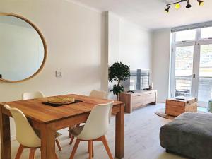 a dining room with a table and a mirror at Waveside Stays in Muizenberg