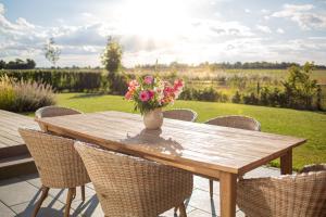 a wooden table with a vase of flowers on it at Feldkoje - Luxuriöses Design-Ferienhaus mit Kamin und Feldrandlage in Fehmarn