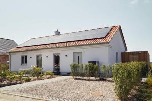a white house with solar panels on the roof at Feldkoje - Luxuriöses Design-Ferienhaus mit Kamin und Feldrandlage in Fehmarn