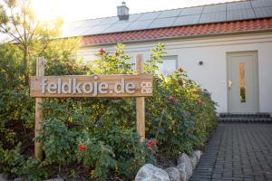 a sign in a garden in front of a house at Feldkoje - Luxuriöses Design-Ferienhaus mit Kamin und Feldrandlage in Fehmarn
