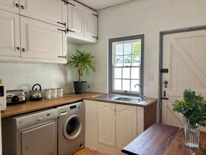 a kitchen with a sink and a washing machine at Little Tara Cottage in Hermanus