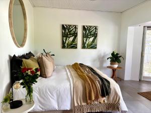 a bedroom with a white bed with a vase of flowers at Little Tara Cottage in Hermanus