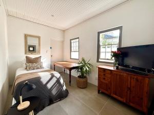 a bedroom with a bed and a flat screen tv at Little Tara Cottage in Hermanus