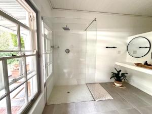 a bathroom with a shower and a sink and a mirror at Little Tara Cottage in Hermanus +12 photos