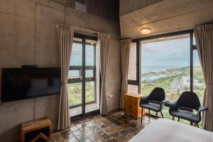 a bedroom with two chairs and a tv and large windows at The Light in Hengchun South Gate