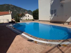 a large blue swimming pool next to a building at Victor Kotor Sea view in Dobrota
