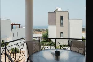 a table on a balcony with a view of a building at Chloraka Sea View Apt with Pool in Khlorakas