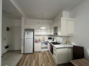 a kitchen with white cabinets and a white refrigerator at Apartment in green Budapest in Tbilisi City