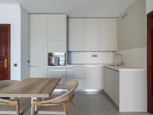 a kitchen with white cabinets and a wooden table at HolaMogamar in Puerto de Mogán
