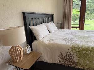 a bedroom with a bed and a table with a lamp at The Sanctuary- Self Catering Accommodation in Nelspruit