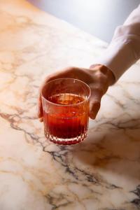 a person holding a drink in a glass on a table at Landgoed Altenbroek in Voeren