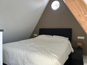 een slaapkamer met een wit bed op zolder bij Luxe Tiny House Ooij in Ooij
