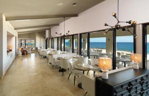 un restaurante con mesas y sillas y el océano en Paradisus Los Cabos - Adults Only - All Inclusive, en Cabo San Lucas