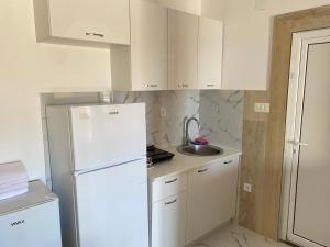 a kitchen with a white refrigerator and a sink at Apartmani Ličina in Bečići