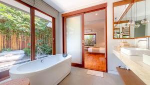 a bathroom with a tub and a sink and a mirror at Agra & Amurti Villas in Munggu +33 photos