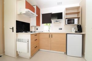 a kitchen with white appliances and wooden cabinets at Camping Héiltzerstee in Rambrouch